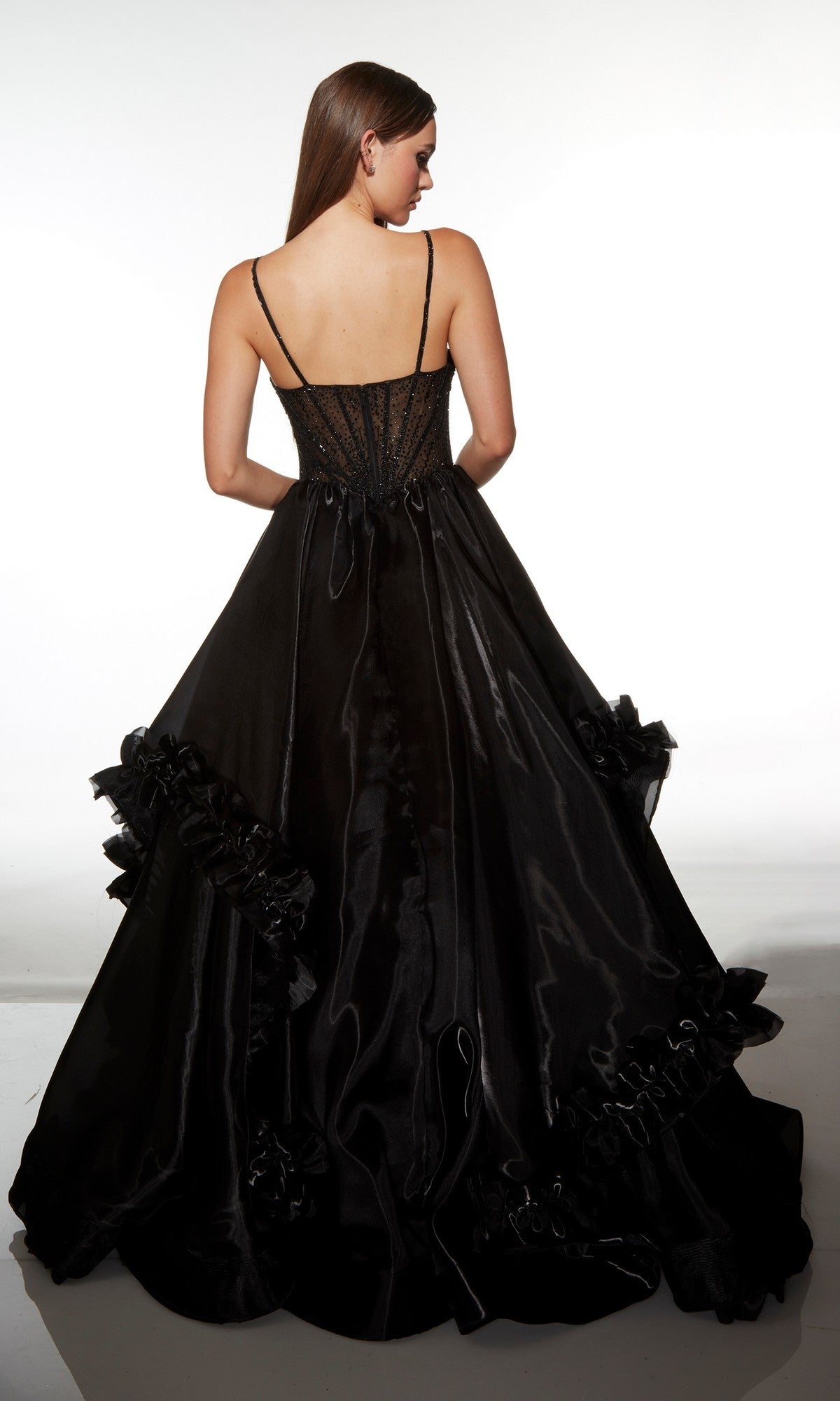 A woman stands with her back to the camera wearing the Alyce 62107 Long Prom Dress, a sleeveless ballgown featuring a corset bodice and ruffled skirt details.